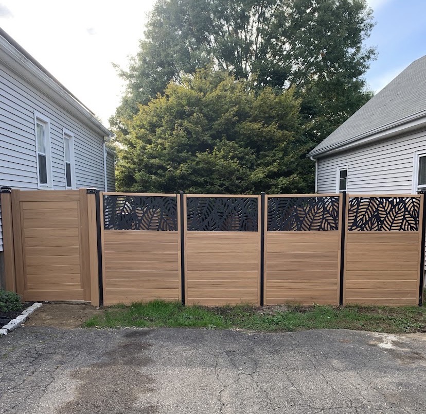 Cedar-tone composite privacy fence with black leaf-pattern decorative screen panels